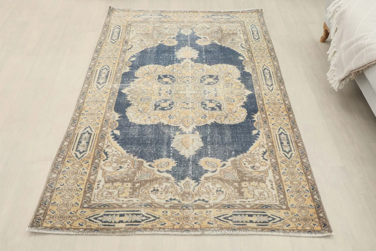 Full overhead view of the navy and tan vintage rug placed on a light floor in a room