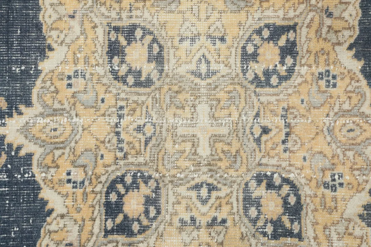 Detailed close-up of the central medallion design with tan, ivory, and navy patterns