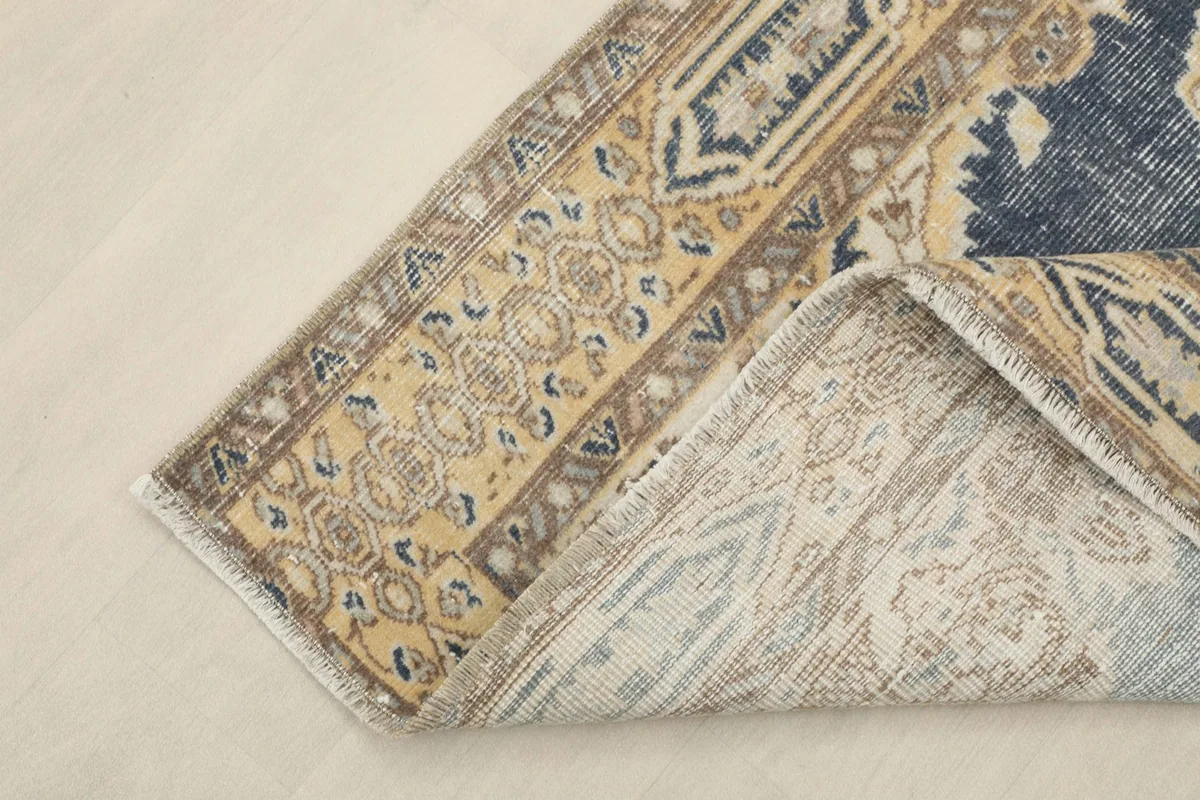 Corner of the rug folded back to reveal the cotton foundation and hand-knotted construction