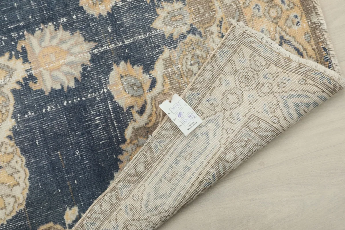 Close-up of the rug's corner with the label, showing the back of the hand-knotted wool pile