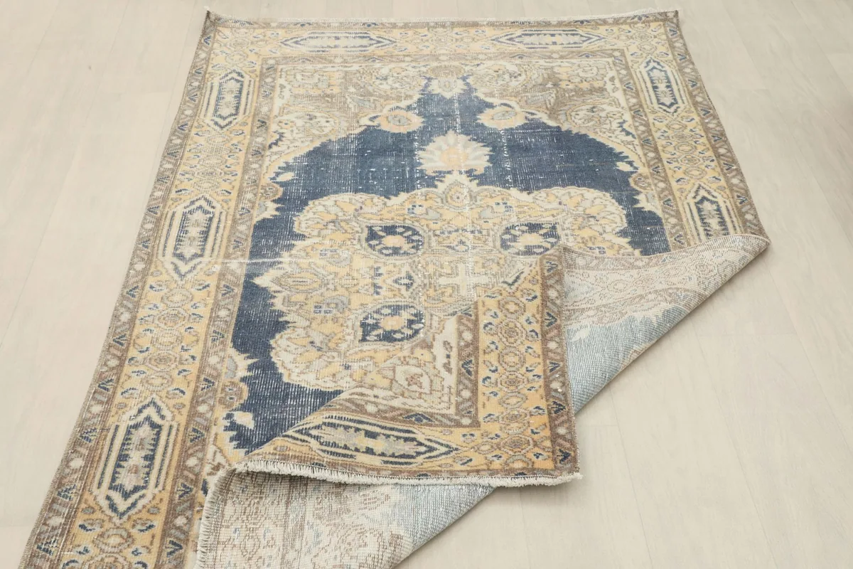 The vintage rug partially folded, showing the reverse side and the overall pattern