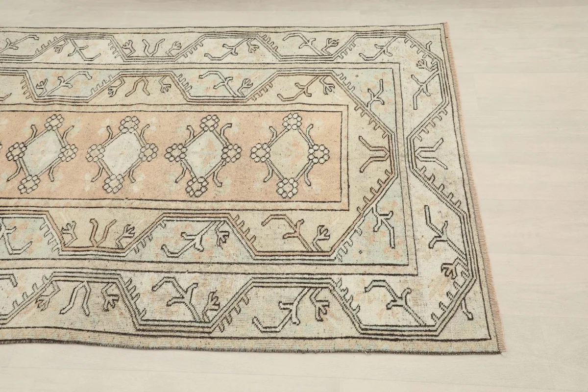 Close-up of the rug's corner, highlighting the beige border and geometric patterns