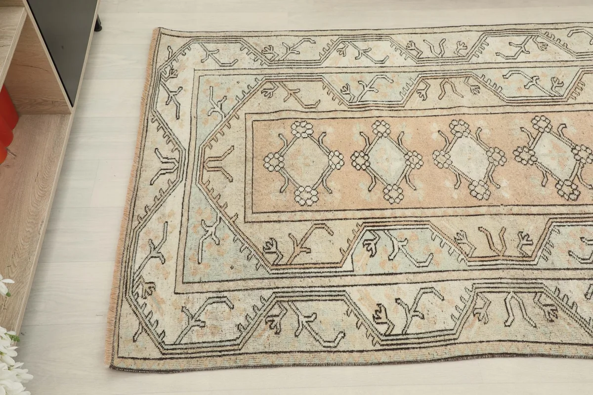 Detail view of the rug's side, showcasing the faded rose field and border design