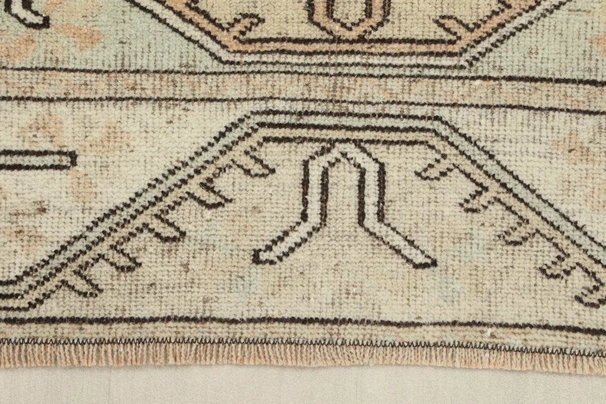 Close-up of the rug's border and fringe, showing the hand-knotted wool texture