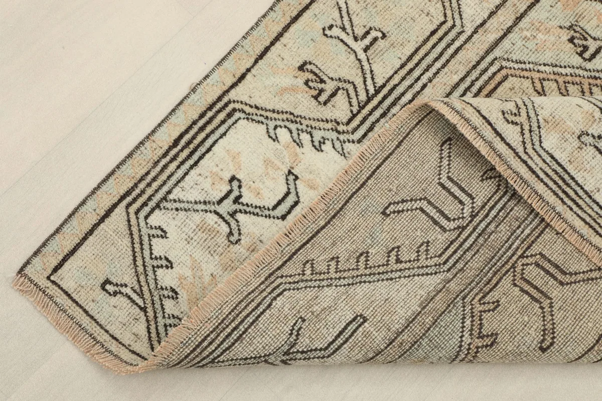 View of the rug folded to show the thickness and the back of the hand-knotted cotton foundation