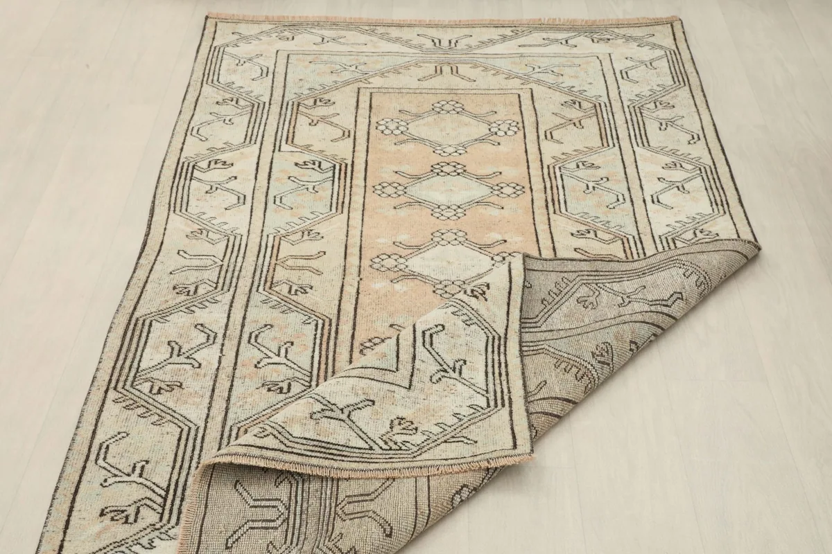 Partially folded rug displaying the full pattern and the pliable nature of the vintage textile