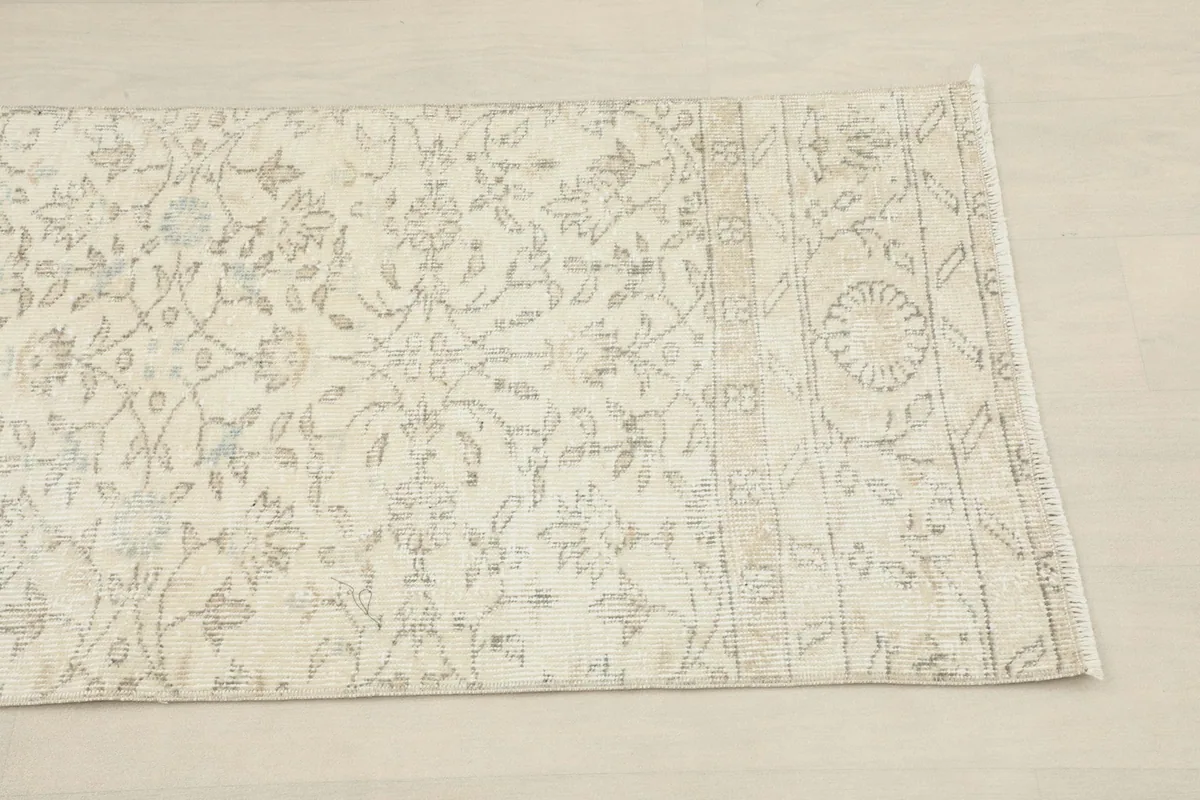 Close-up of one end of the runner rug, highlighting the faded botanical and border patterns
