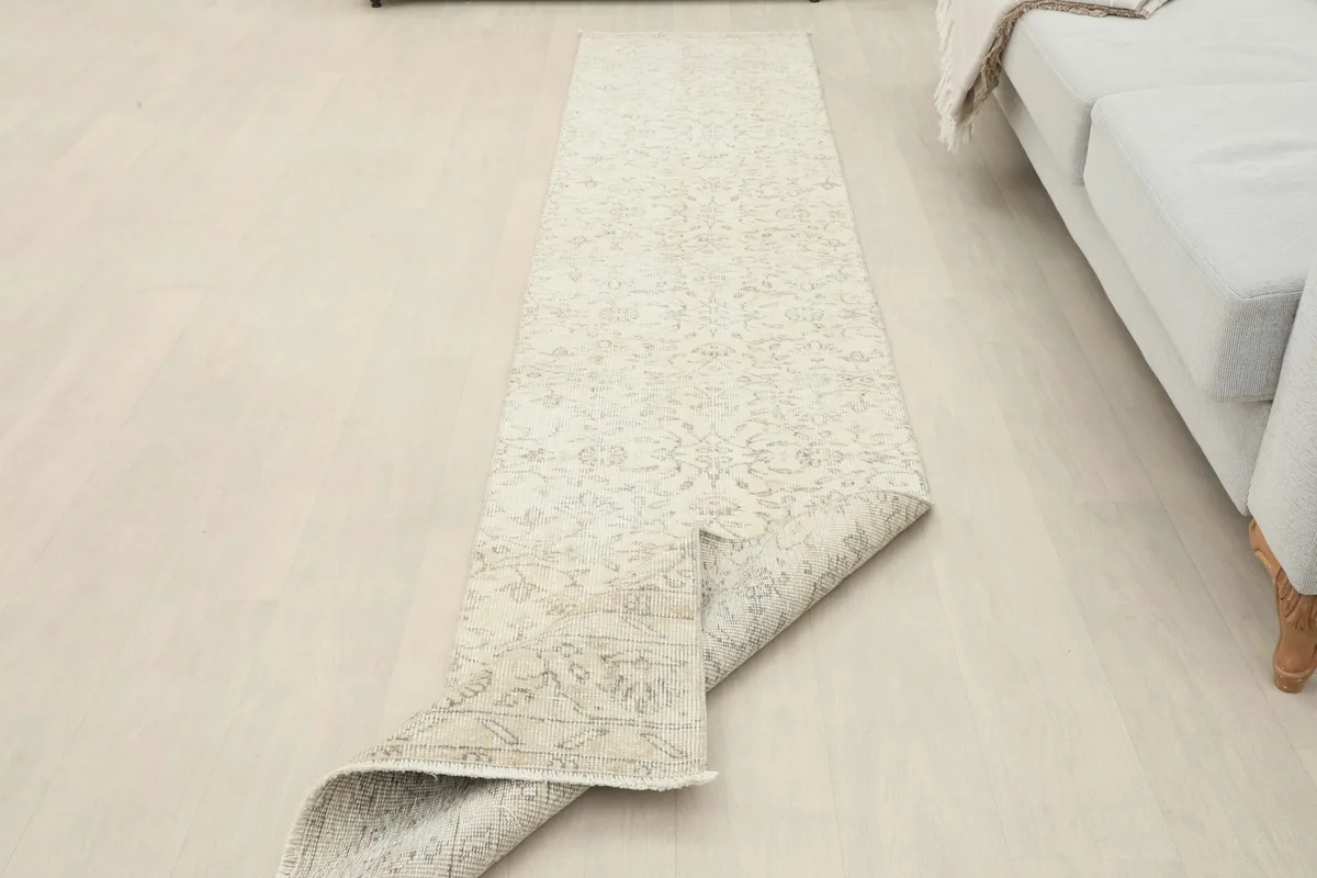 Runner rug partially folded back, revealing the underside and its placement in the room