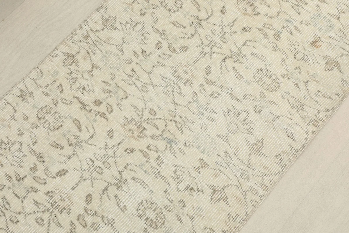 Overhead shot of the runner rug, focusing on the central botanical design and muted tones
