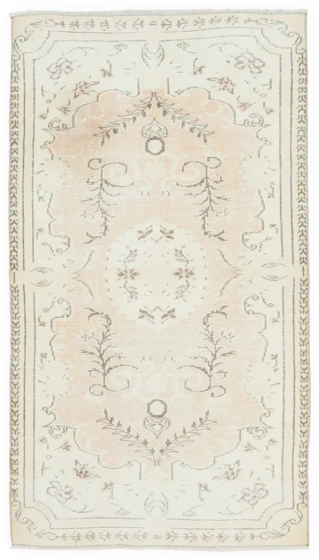 Full overhead view of a beige and rose vintage Anatolian rug with floral and medallion patterns