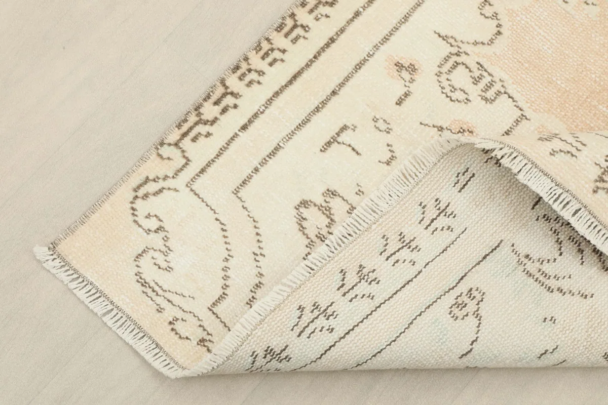 Corner of the rug folded to show the back of the hand-knotted wool pile and cotton foundation