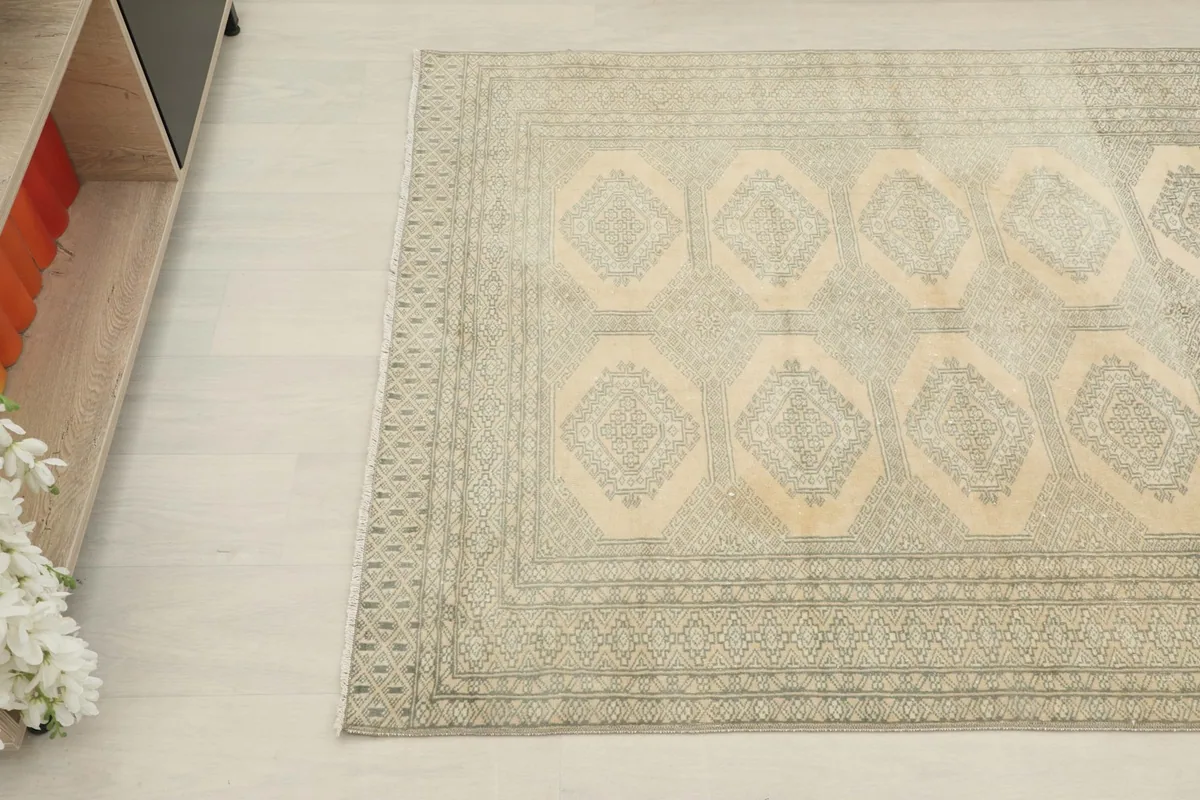 Overhead angled view showing the beige field and charcoal geometric motifs of the rug.