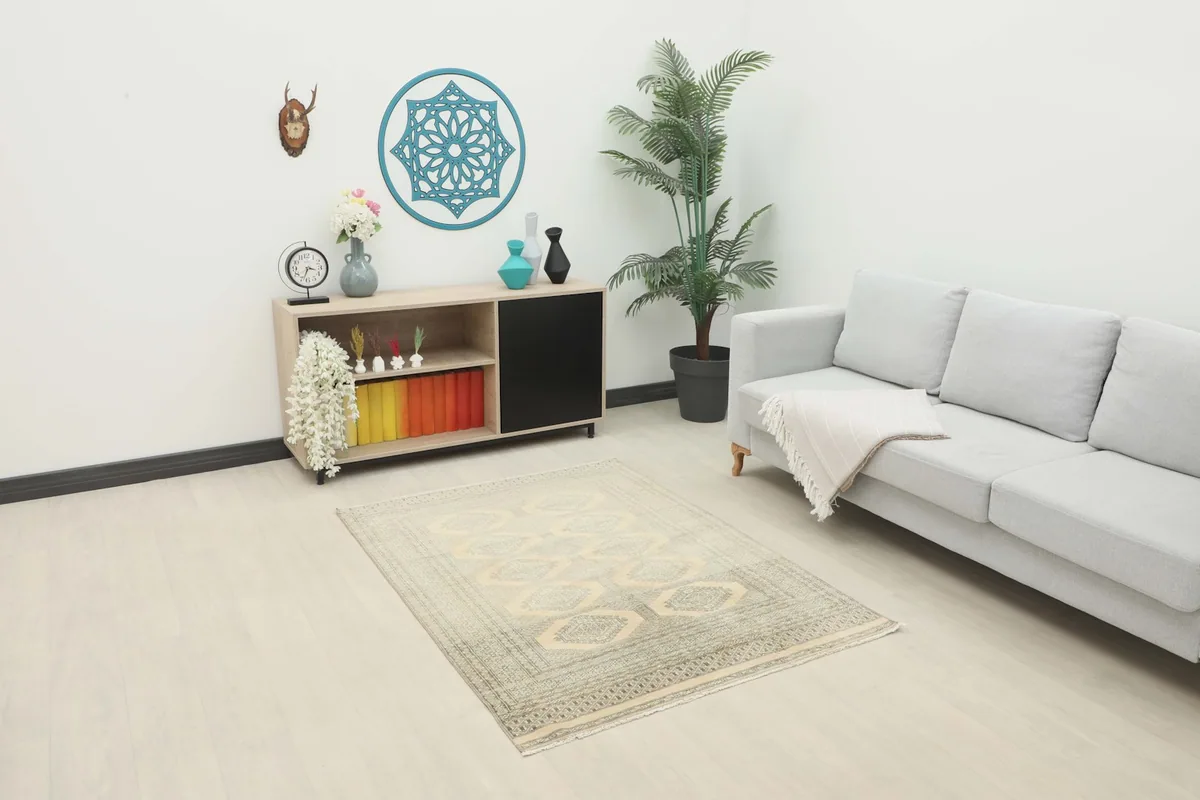 Vintage beige and charcoal rug placed in a living room setting with a sofa and cabinet.