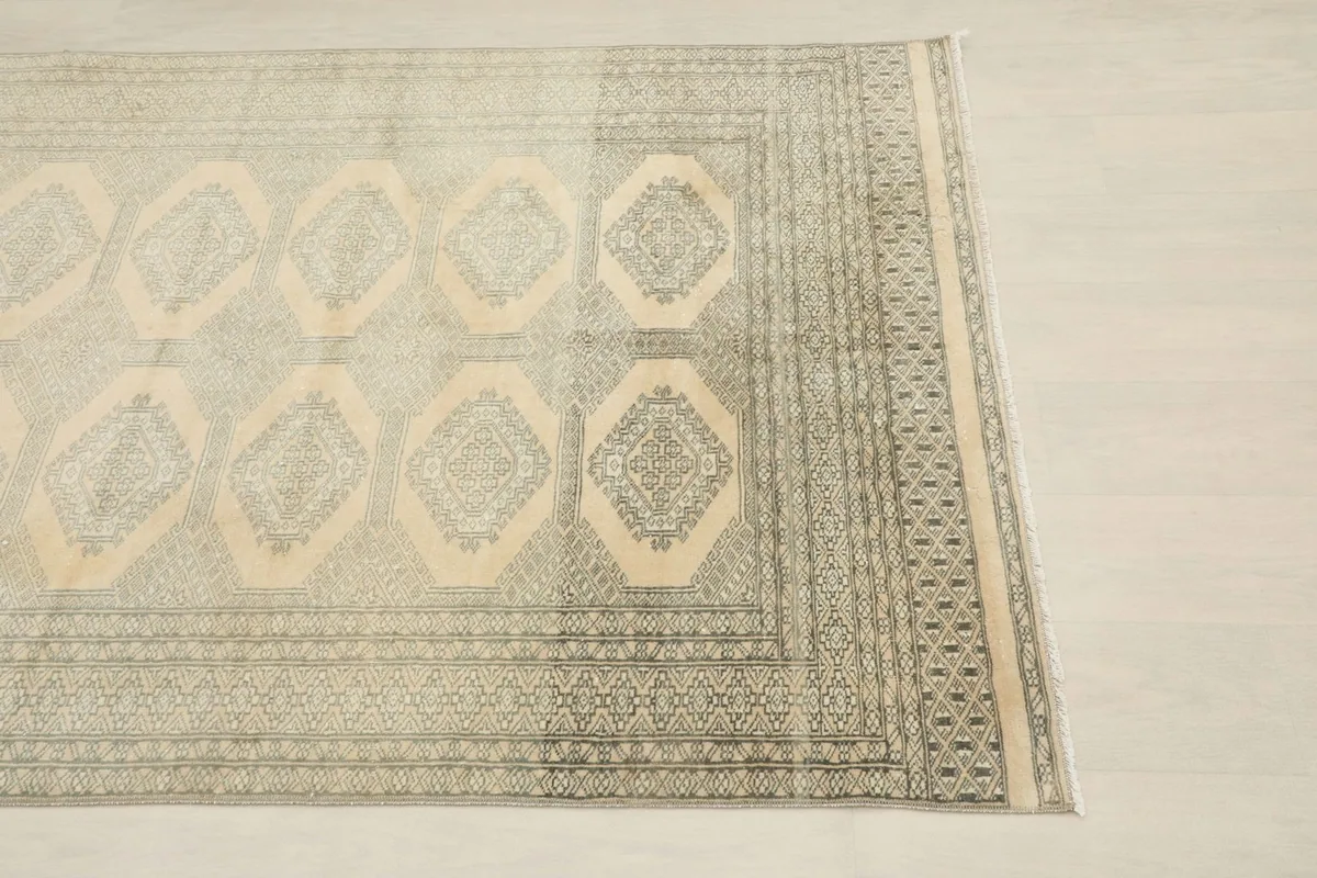 Close-up view of the intricate geometric patterns and border on the vintage rug.