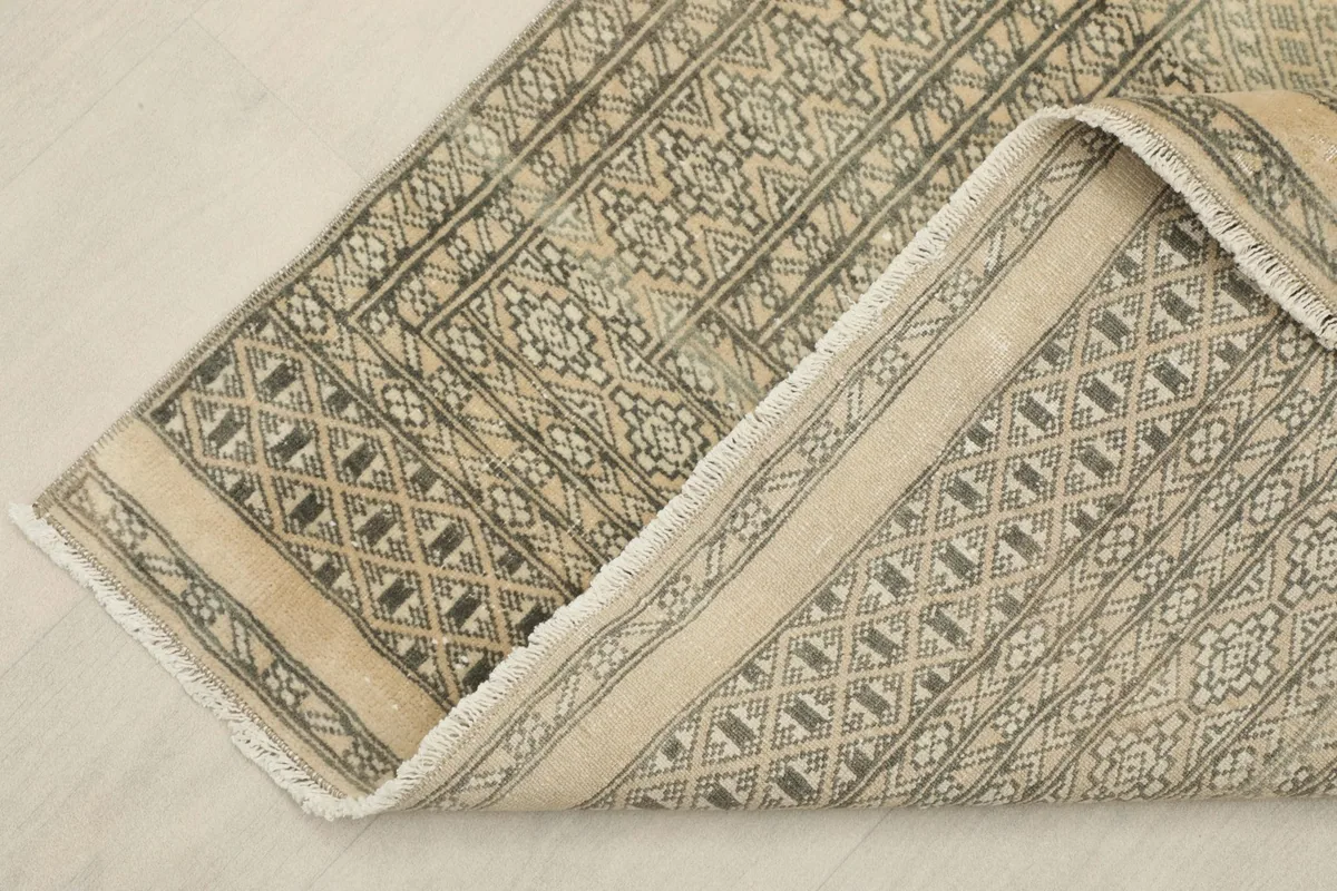 Corner of the rug folded back, revealing the wool pile and cotton foundation.