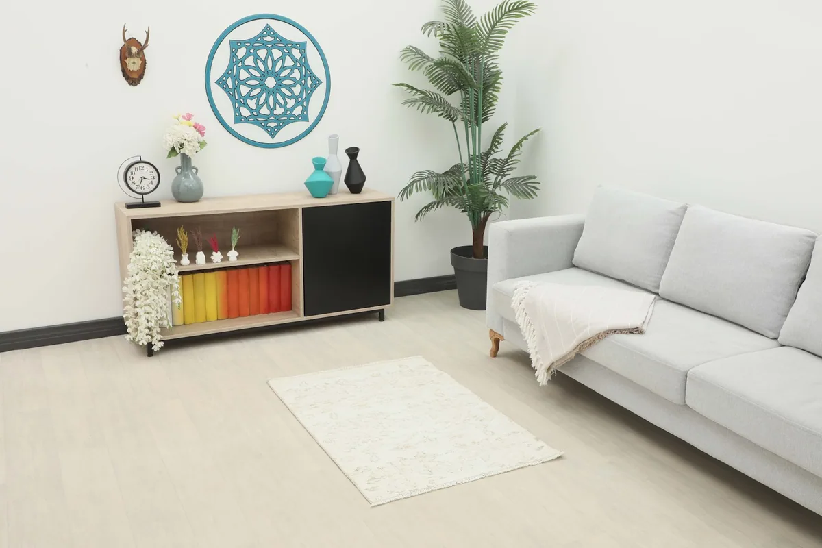 Ivory and beige vintage rug placed in a modern living room setting with a light gray sofa and wooden cabinet.