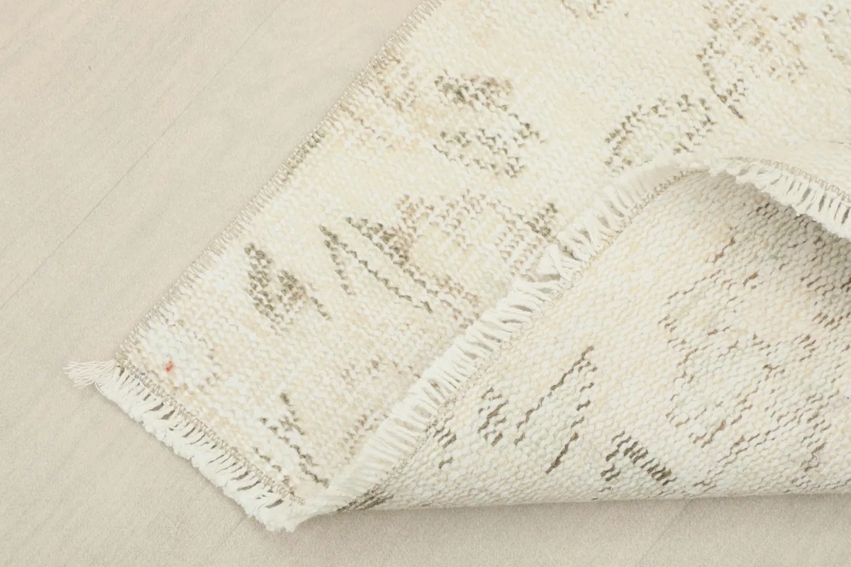Corner of the rug folded over to show the cotton foundation and the reverse side of the hand-knotted wool pile.