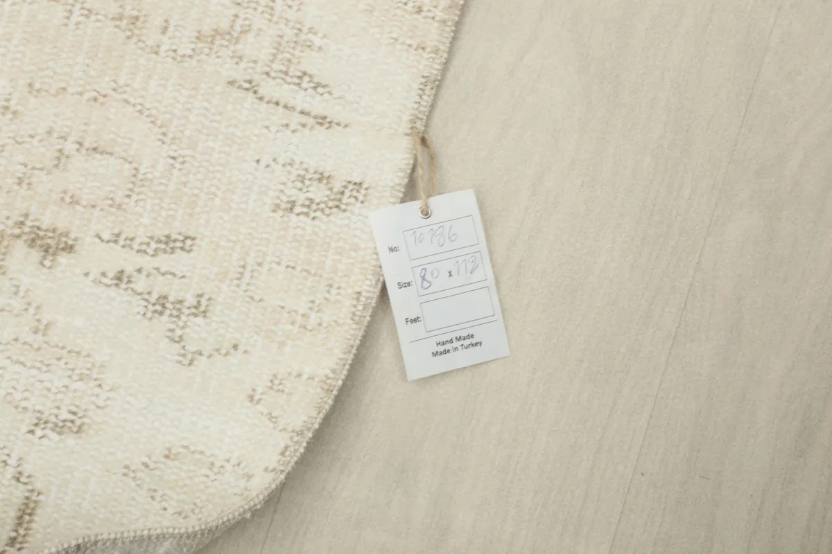 Corner of the rug with a product tag, showing details like size and origin, on a light background.