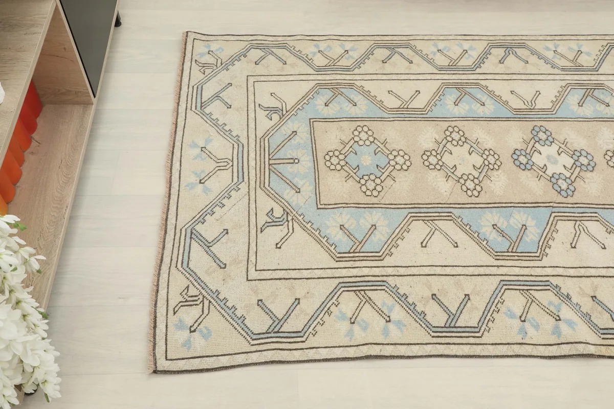 Overhead angle shot of the rug's pattern, featuring the beige field and blue geometric shapes