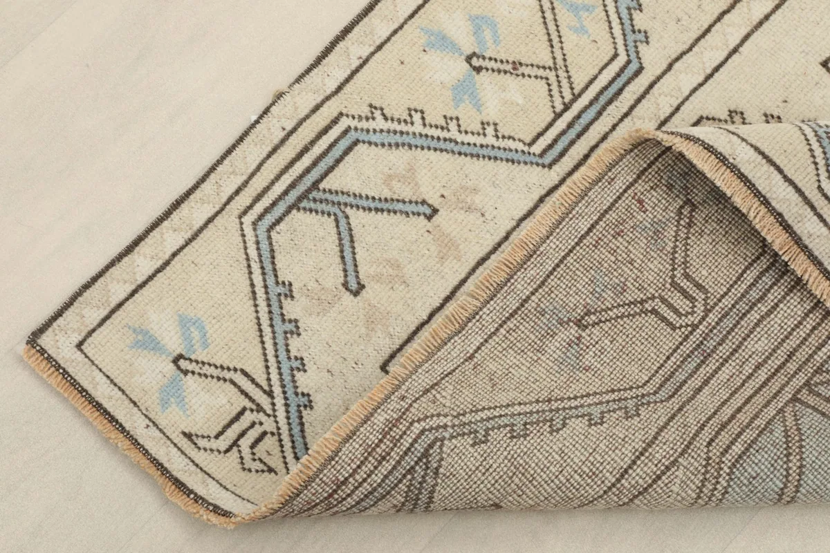 Corner of the rug folded back, revealing the cotton foundation and the reverse side of the knots