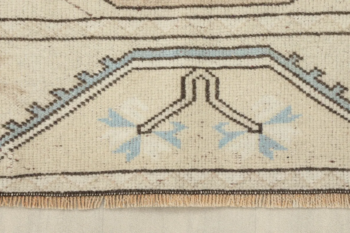 Close-up of the rug's fringe and a section of the border pattern, showing the hand-knotted detail