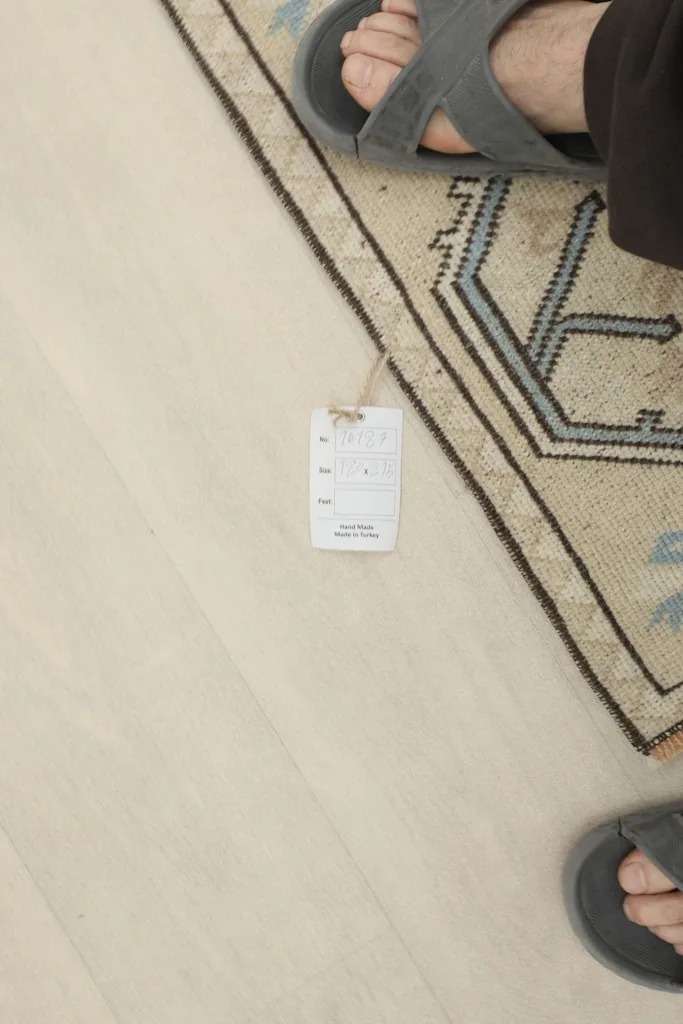 Foot and size tag near the rug, indicating its small size and authentic vintage quality