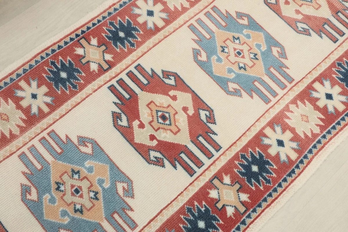 Angled detail shot of the rug's central motifs and the red patterned border