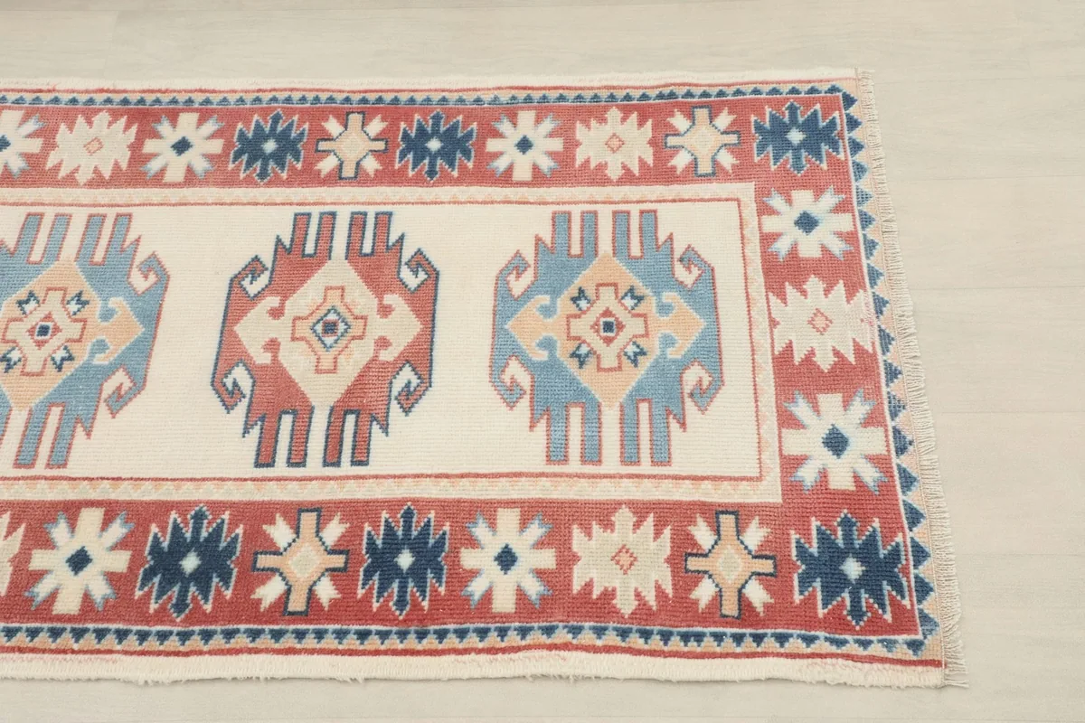 Close-up of one end of the runner rug, showing the red border and ivory field motifs