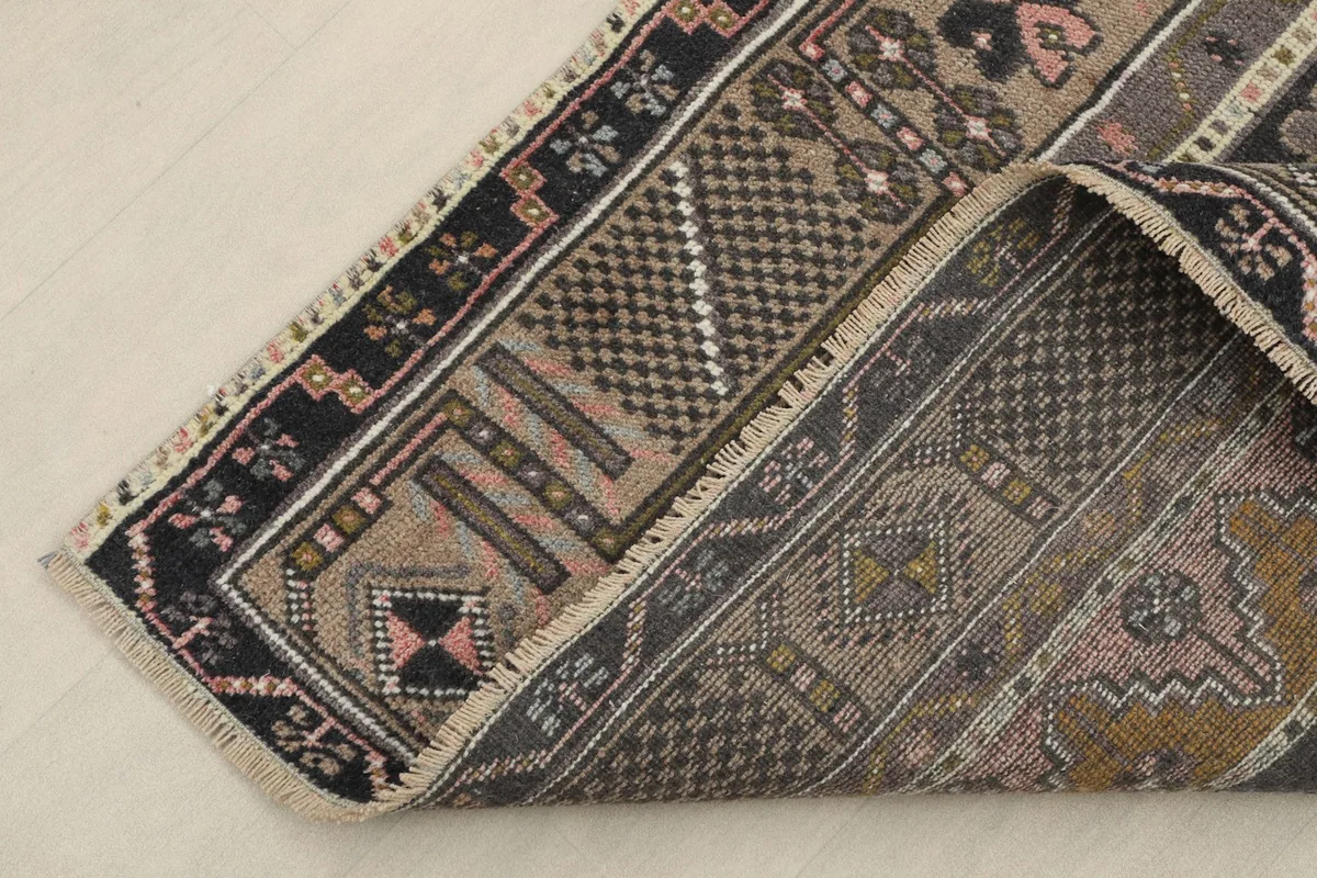 View of the rug's backside and folded corner, revealing the hand-knotted cotton foundation.