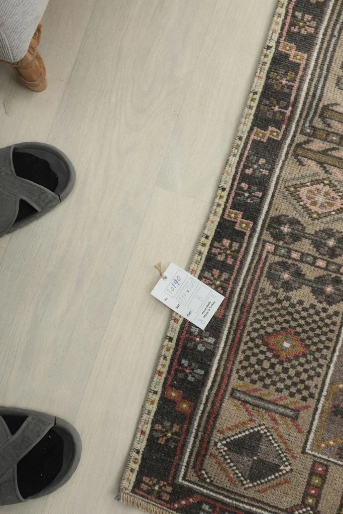 Overhead shot of the rug's edge with a size tag and slippers for scale.