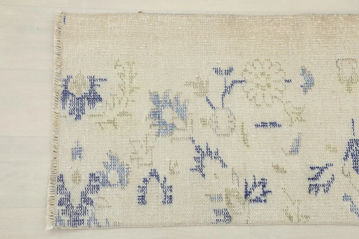 Close-up of the other end of the rug, displaying the subtle variations in the ivory and colored patterns.