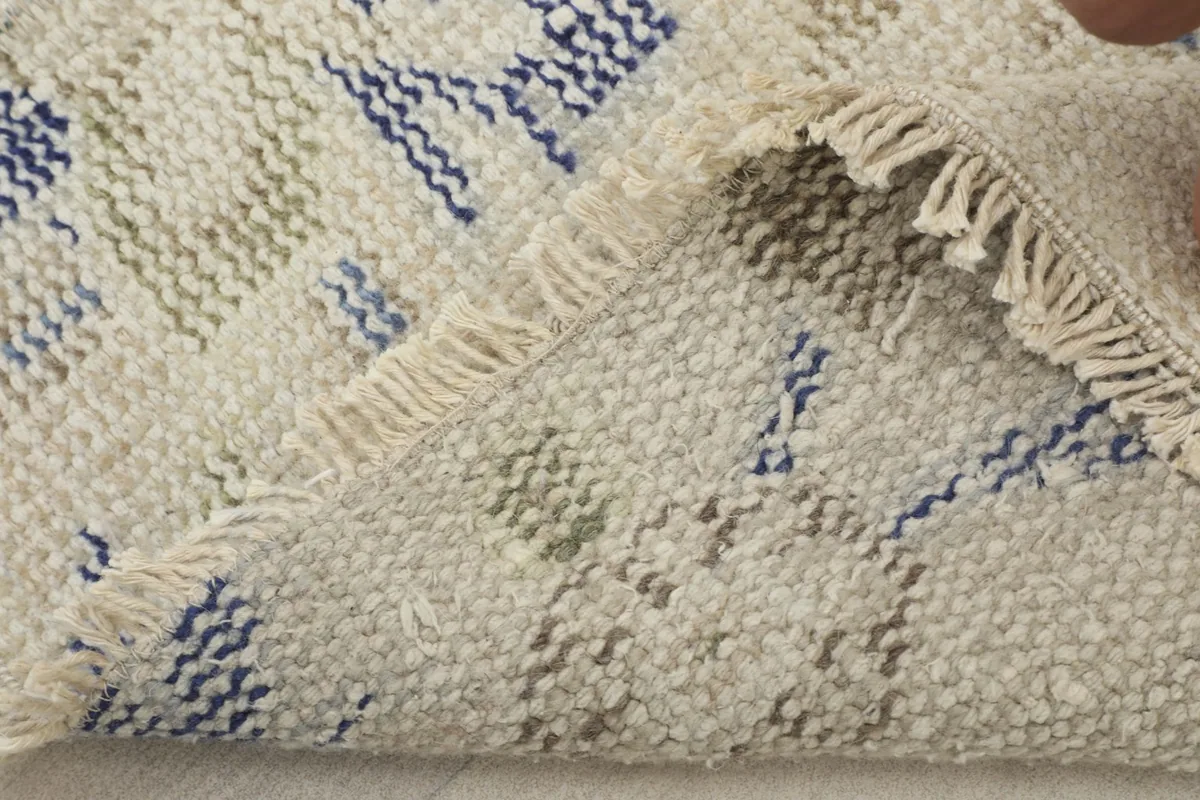 Corner of the rug folded back to reveal the cotton foundation and the hand-knotted construction.