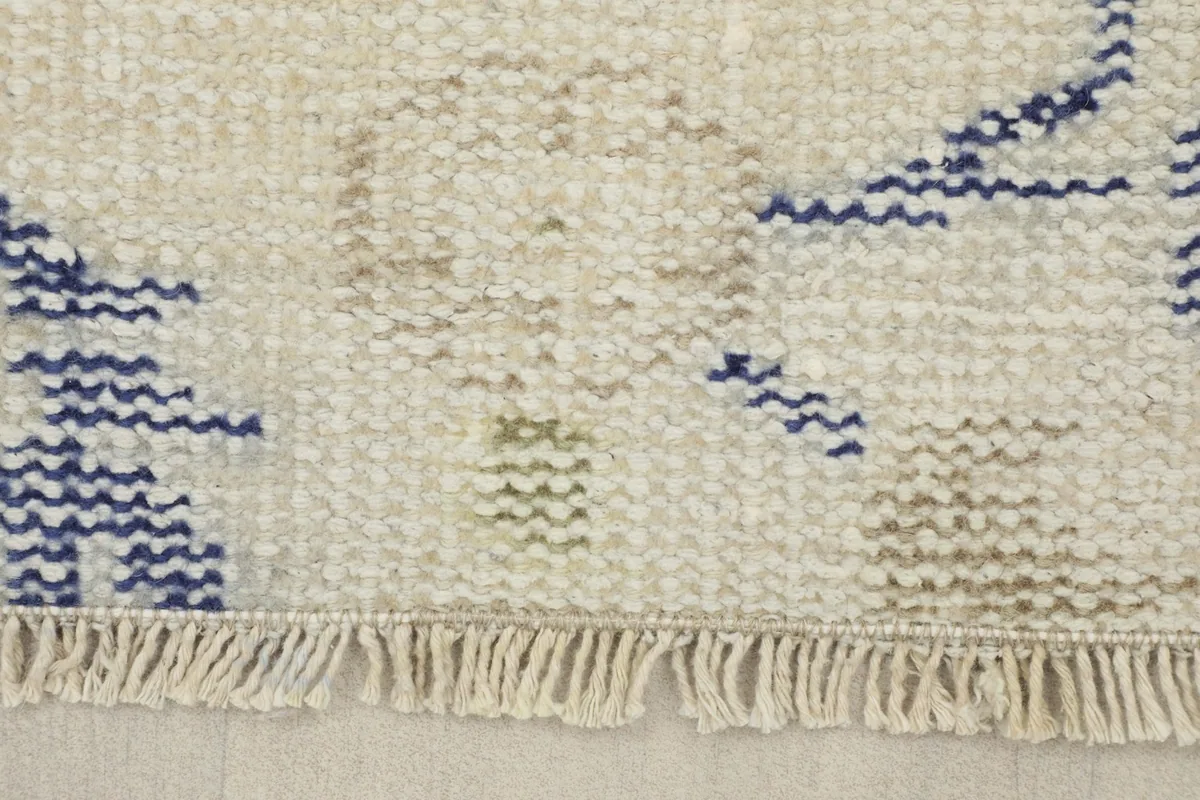 Close-up of the short, natural ivory fringes and the edge of the rug, showing the low pile.
