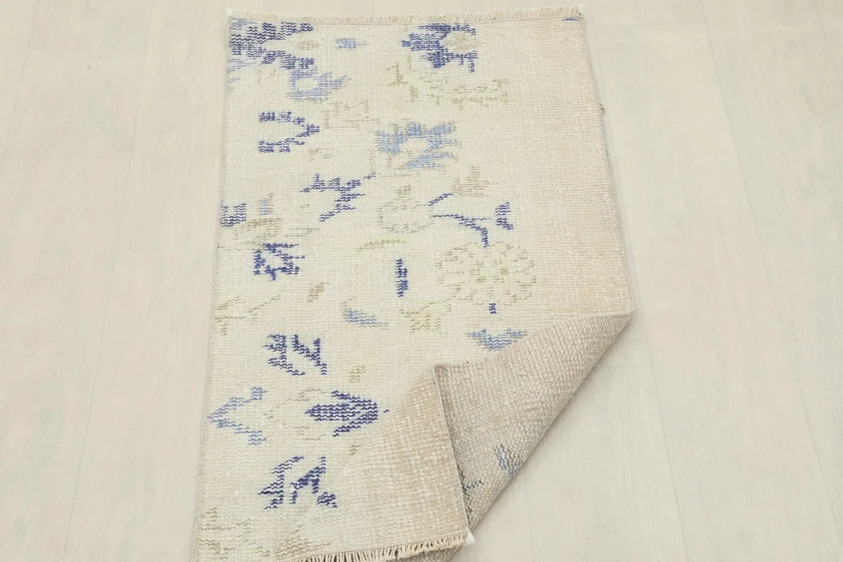 Overhead view of the rug with one corner folded back, showing both the front and back of the weave.