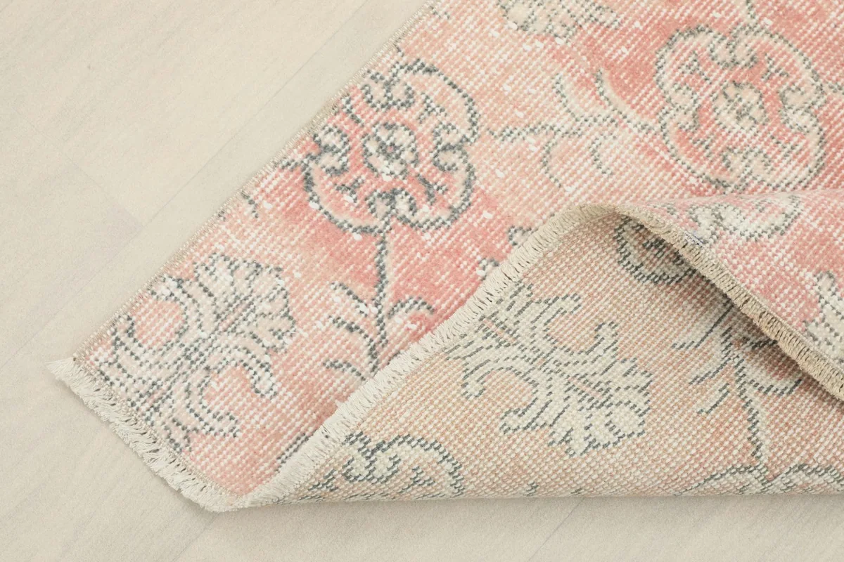 Corner of the rug folded back to reveal the cotton foundation and reverse side