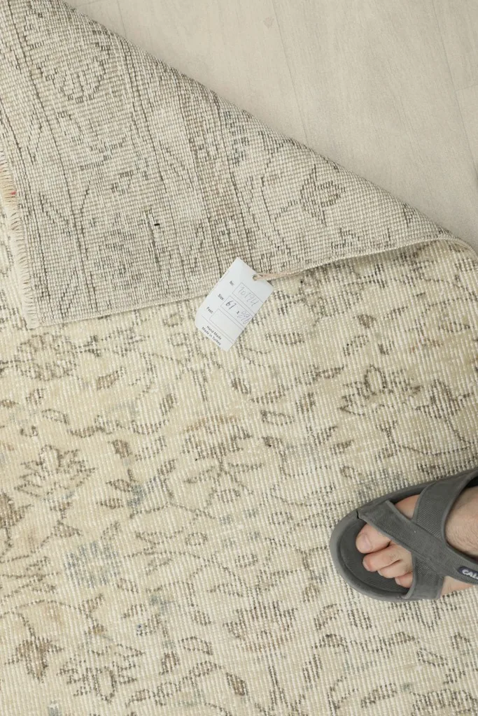 Top-down view of the runner with a corner folded, exposing the back of the rug and foundation.