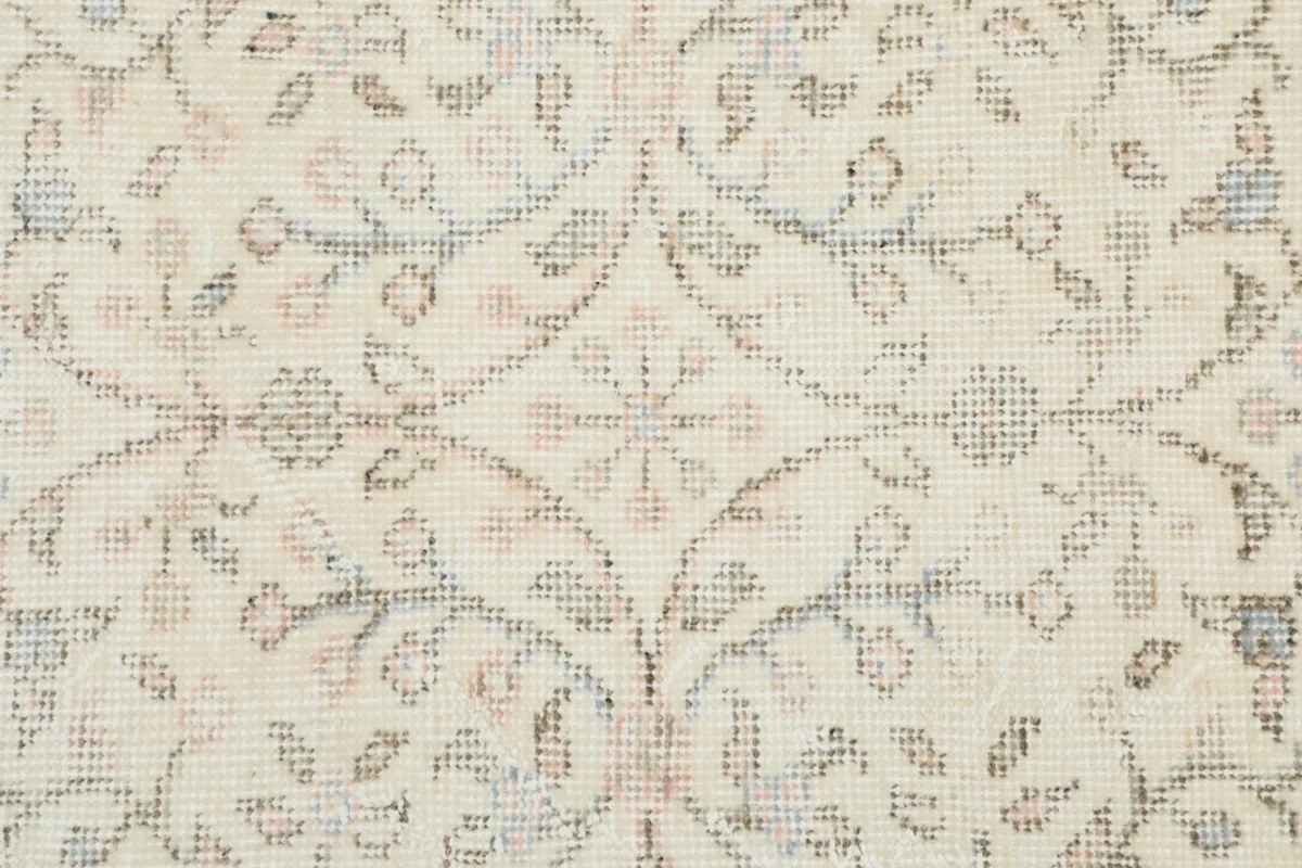 Detailed close-up of the rug's pile, showing the texture and faded colors of the floral design.