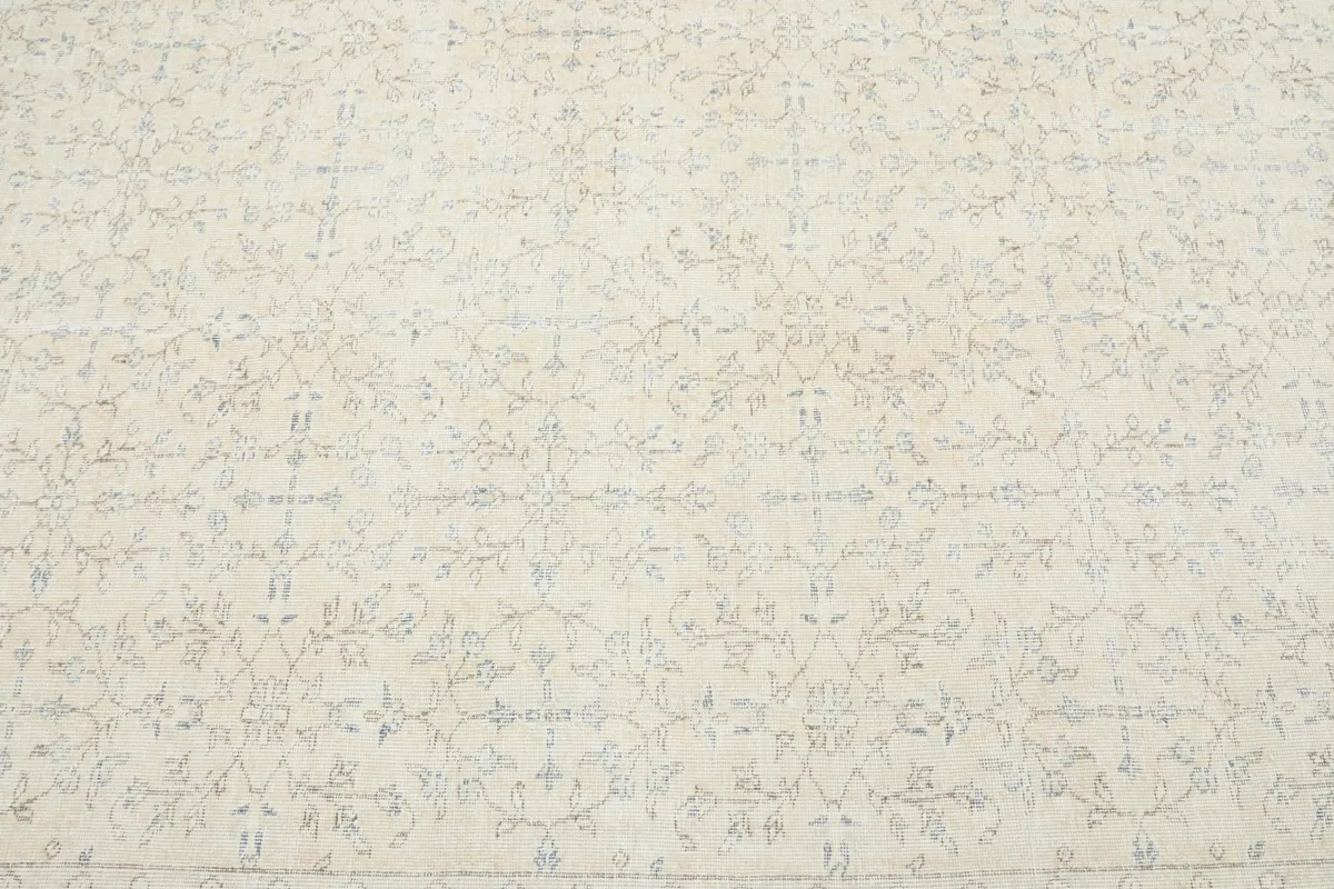 Close-up of the ivory field with subtle blue and tan floral motifs