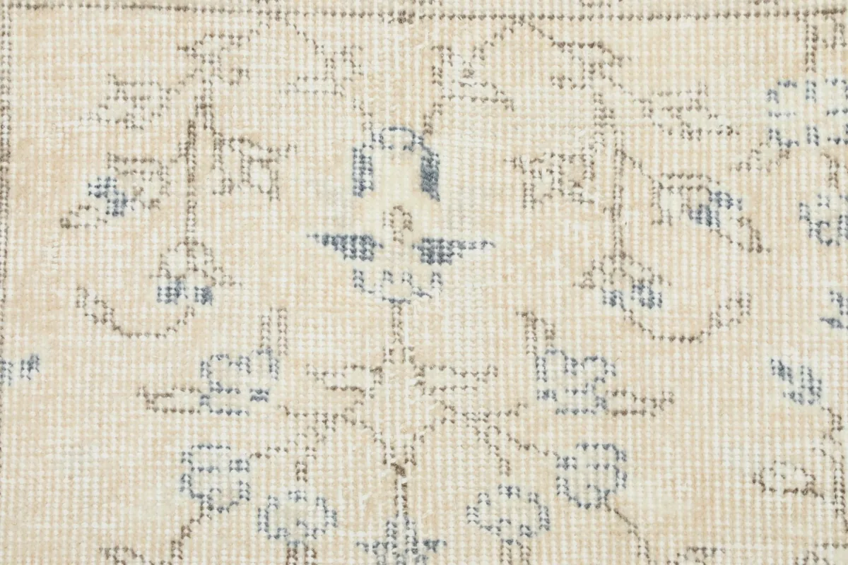 Detailed view of the hand-knotted wool pile and faded blue floral design