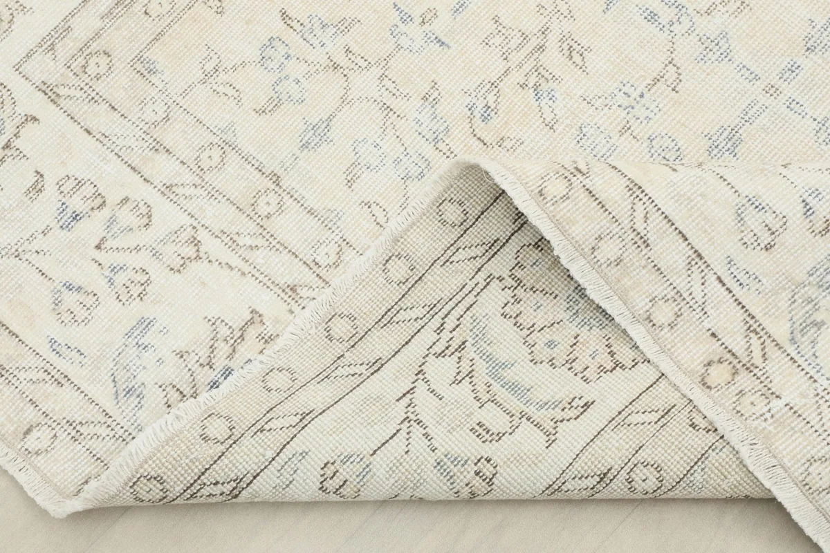 Folded corner of the rug revealing the wool pile and cotton foundation