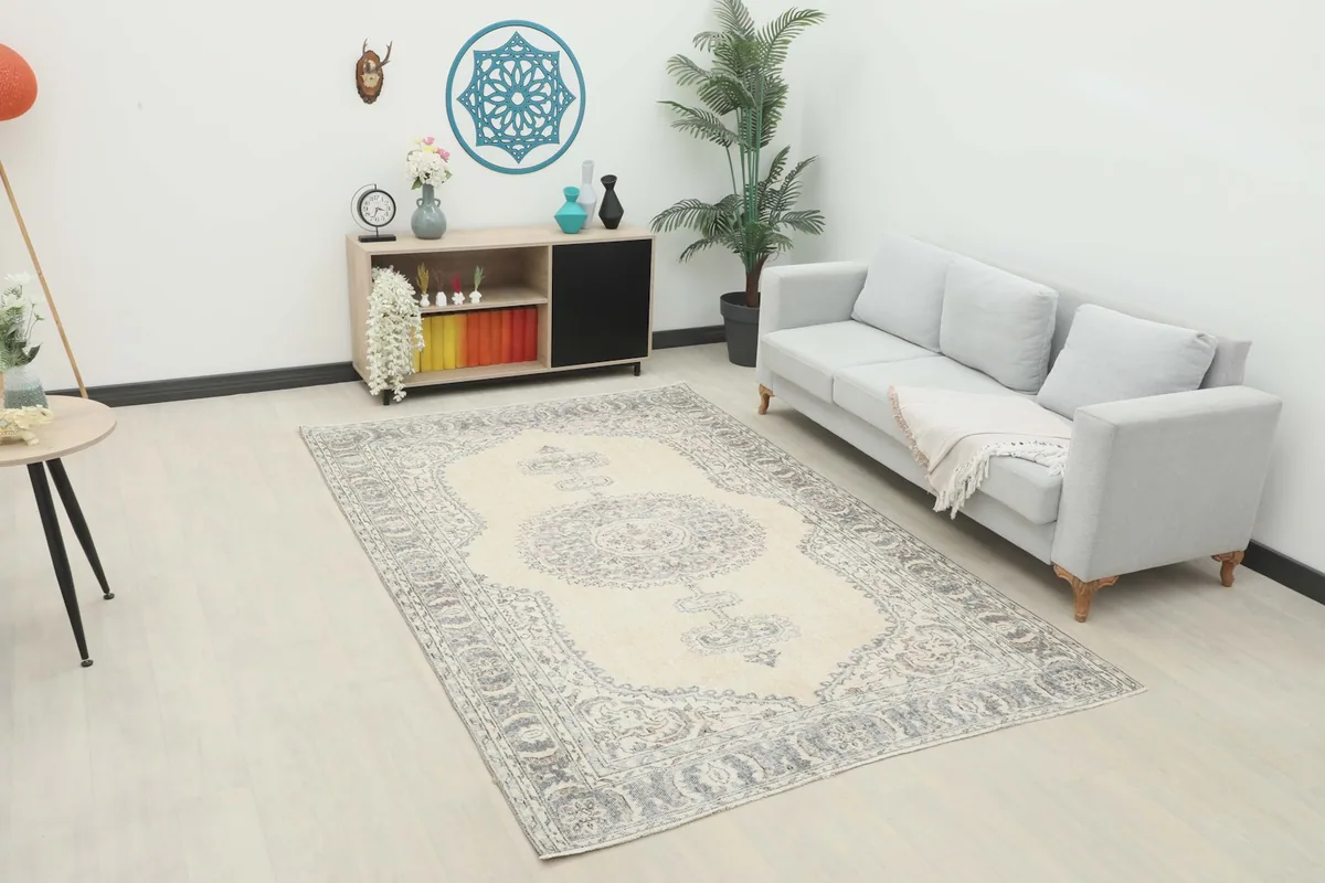 Vintage Anatolian rug displayed in a bright room setting with a light gray sofa and modern decor.