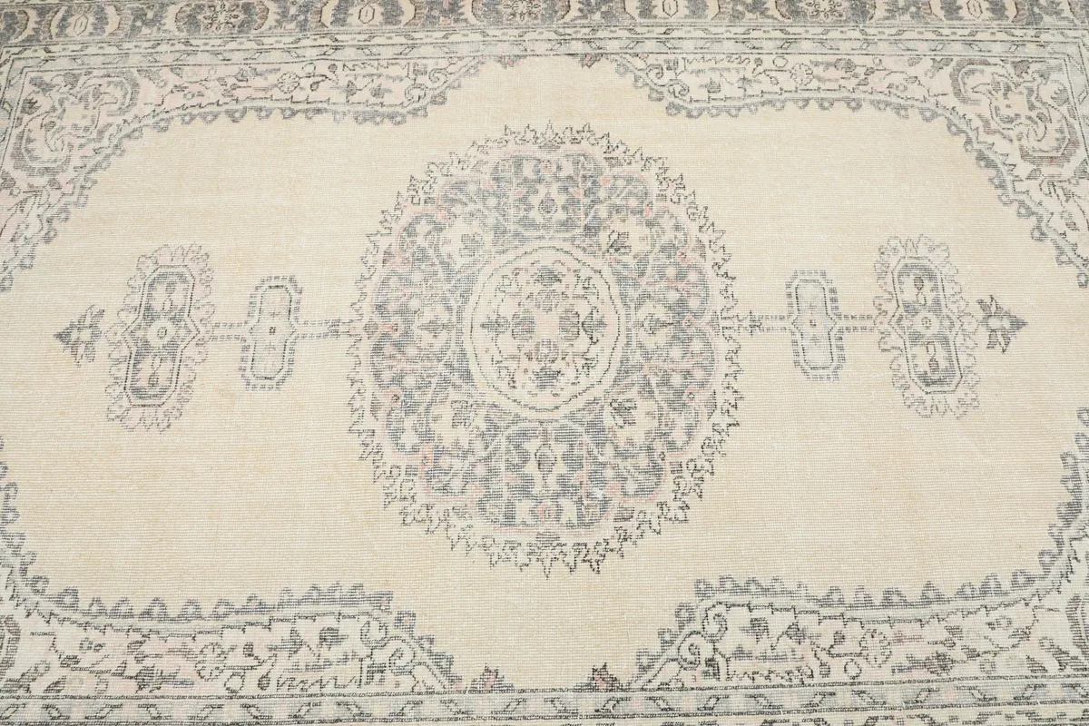 Detailed overhead view of the central medallion and surrounding motifs in gray on the ivory rug.