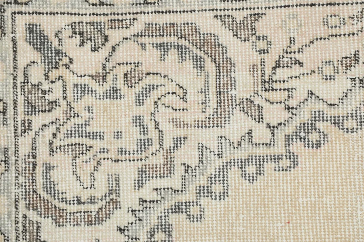 Close-up detail of the hand-knotted wool pile and intricate gray patterns on the ivory background.