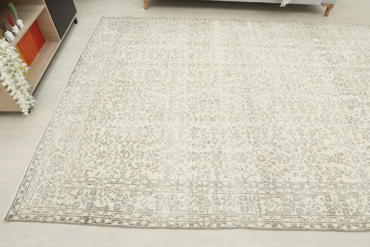 Angled perspective of the rug, displaying its full size and subtle gray patterns across the cream field.