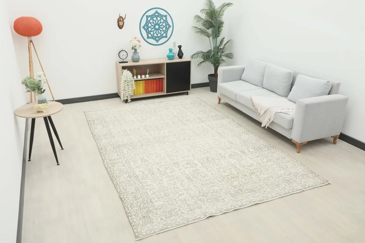 Large cream and gray vintage rug shown in a modern living room setting with a sofa and decor.