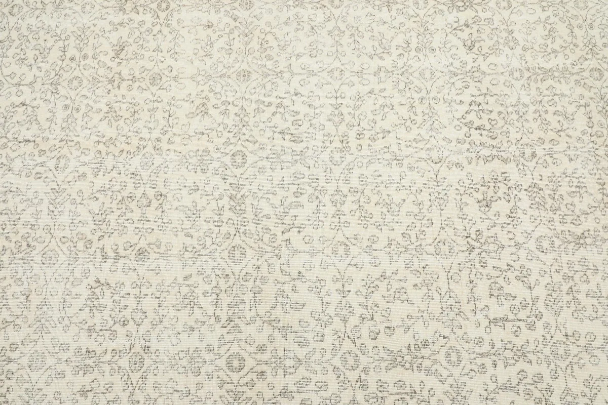 Detailed view of the rug's cream field with intricate gray floral and vine motifs.