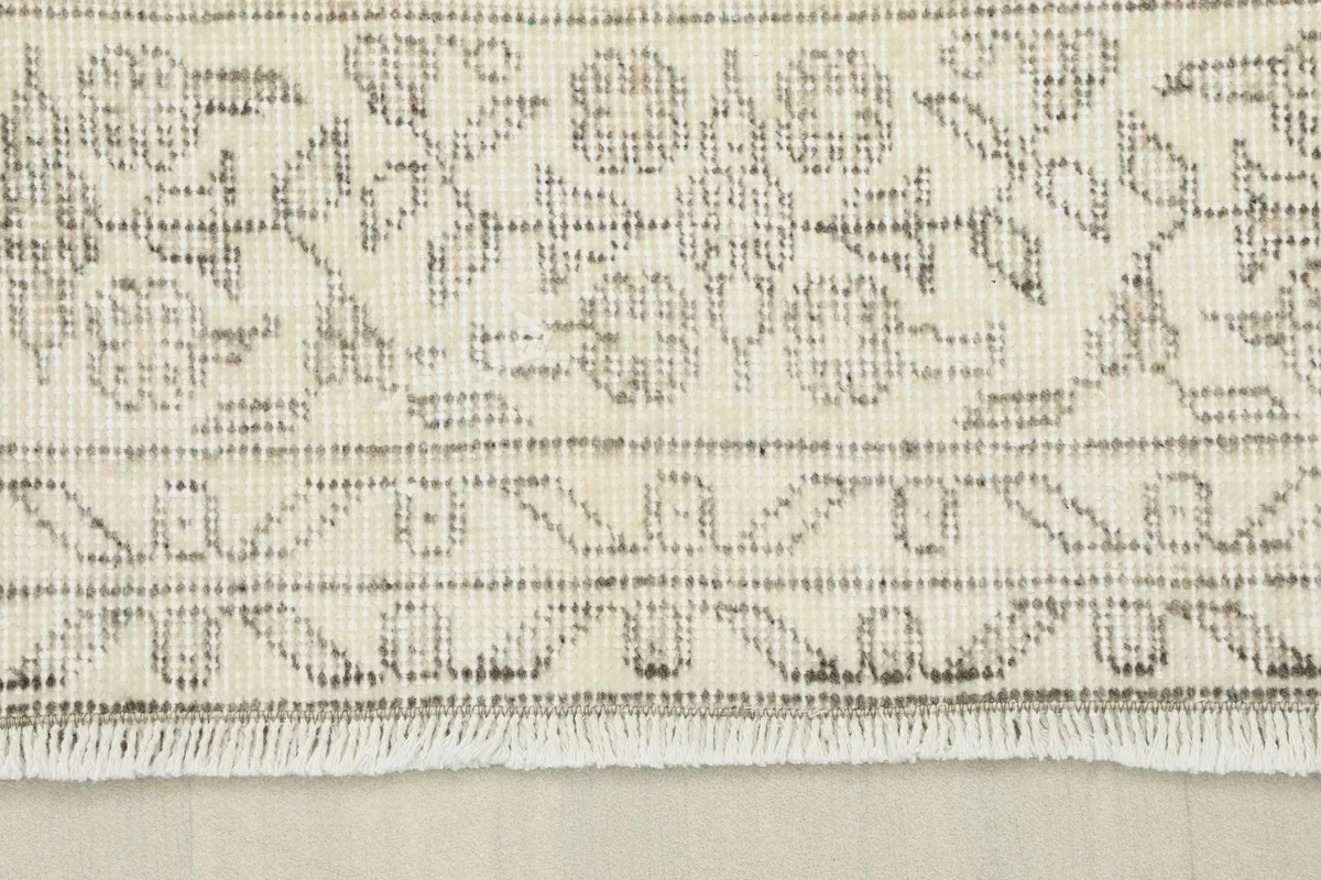 Close-up of the rug's border, showcasing the geometric gray patterns and short fringe.