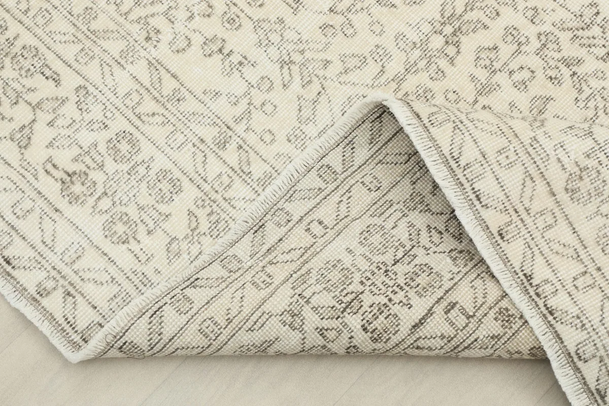 Corner of the rug folded back, revealing the wool pile and cotton foundation.