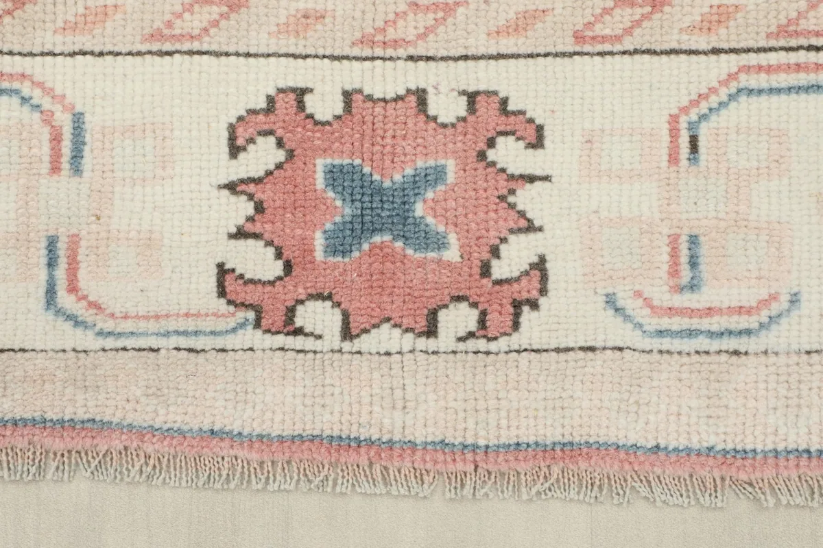 Close-up of the ivory border showing a tribal motif in rose and blue