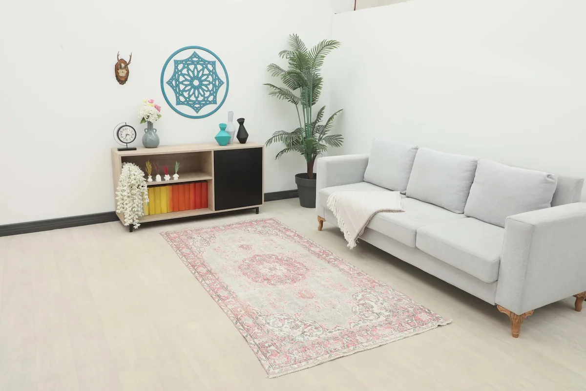Vintage gray and rose rug displayed in a bright living room setting with a sofa.